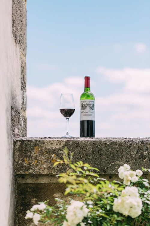 Verre et bouteille de vin Château Canon posés sur un mur